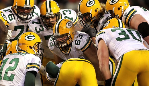The Green Bay Packers huddle up on the ball.